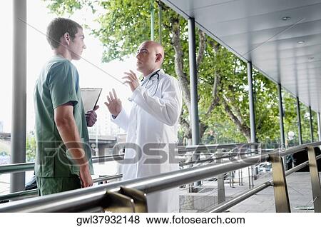 Doctor talking to a male nurse View Large Photo Image Stock Photo - Doctor talking to a male nurse. Fotosearch