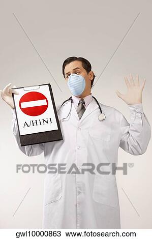 Stock Image - Doctor wearing a flu mask and showing Do Not Enter sign. Fotosearch
