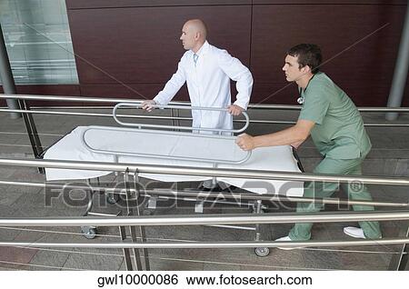 Stock Photograph - Doctor with a male nurse pushing a stretcher. Fotosearch