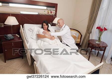 Doctor with a woman holding her newborn baby in a hospital View Large Photo Image Picture - Doctor with a woman holding her newborn baby in a hospital. Fotosearch