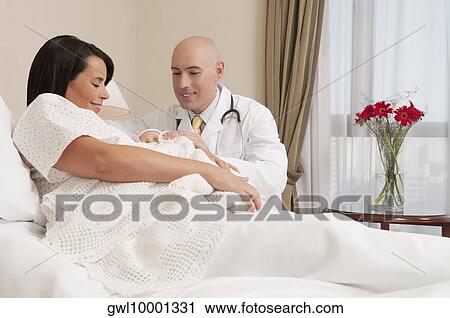 Doctor with a woman holding her newborn baby in a hospital View Large Photo Image Stock Image - Doctor with a woman holding her newborn baby in a hospital. Fotosearch
