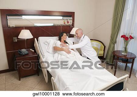 Doctor with a woman holding her newborn baby in a hospital View Large Photo Image Stock Photo - Doctor with a woman holding her newborn baby in a hospital. Fotosearch