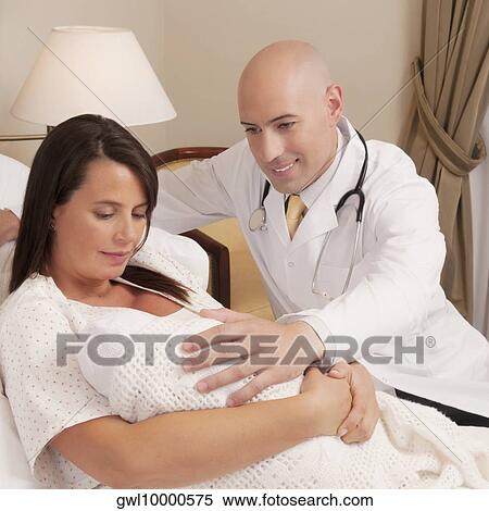 Doctor with a woman holding her newborn baby in a hospital View Large Photo Image Stock Photography - Doctor with a woman holding her newborn baby in a hospital. Fotosearch
