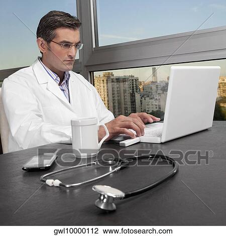 Stock Image - Doctor working on a laptop. Fotosearch