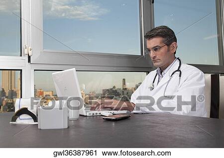 Doctor working on a laptop View Large Photo Image Stock Image - Doctor working on a laptop. Fotosearch