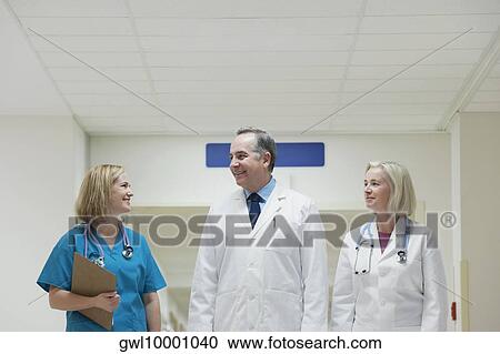 Doctors and a nurse standing in a hospital corridor View Large Photo Image Stock Image - Doctors and a nurse standing in a hospital corridor. Fotosearch