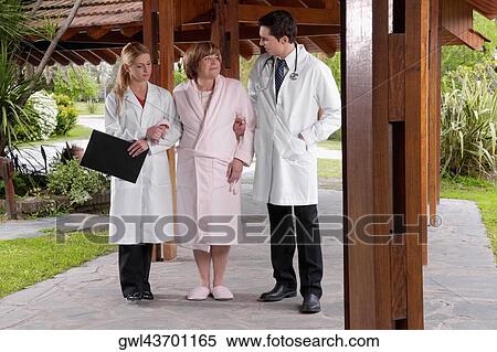 Stock Photography - Doctors assisting a patient in walking in a rehabilitation centre. Fotosearch