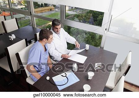 Stock Photography - Doctors discussing a medical report in a cafeteria. Fotosearch