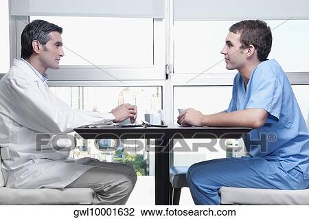 Stock Image - Doctors discussing in a cafeteria. Fotosearch