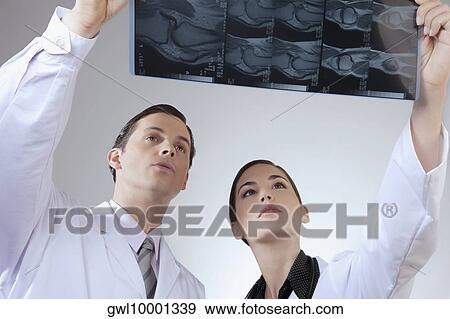 Doctors examining an x-ray report View Large Photo Image Stock Photo - Doctors examining an x-ray report. Fotosearch