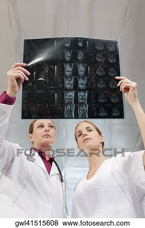 Doctors examining an X-Ray report View Large Photo Image Stock Photo - Doctors examining an X-Ray report. Fotosearch