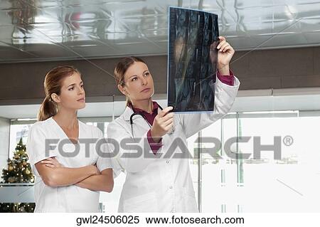 Doctors examining an X-Ray report View Large Photo Image Stock Photography - Doctors examining an X-Ray report. Fotosearch