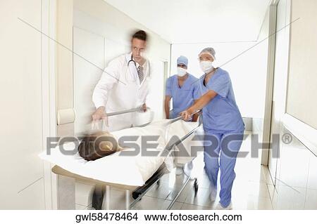 Doctors pushing a patient on a hospital Gurney in a hospital corridor View Large Photo Image Picture - Doctors pushing a patient on a hospital Gurney in a hospital corridor. Fotosearch