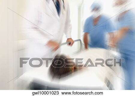 Doctors pushing a patient on a hospital Gurney in a hospital corridor View Large Photo Image Stock Image - Doctors pushing a patient on a hospital Gurney in a hospital corridor. Fotosearch