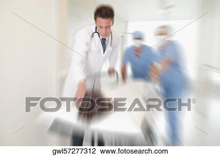 Doctors pushing a patient on a hospital Gurney in a hospital corridor View Large Photo Image Stock Image - Doctors pushing a patient on a hospital Gurney in a hospital corridor. Fotosearch