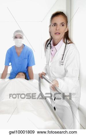Doctors pushing a patient on a hospital Gurney in a hospital corridor View Large Photo Image Stock Photo - Doctors pushing a patient on a hospital Gurney in a hospital corridor. Fotosearch