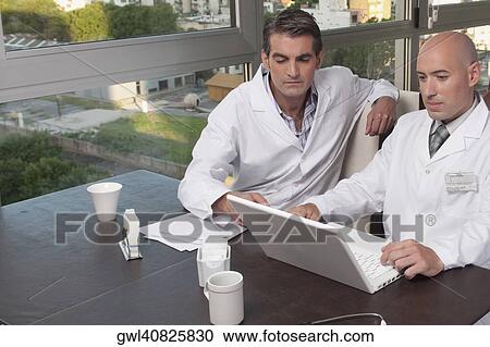 Doctors using a laptop in a cafeteria View Large Photo Image Stock Image - Doctors using a laptop in a cafeteria. Fotosearch
