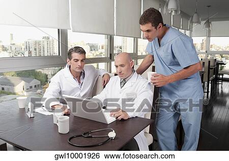 Doctors using a laptop in a cafeteria View Large Photo Image Stock Photograph - Doctors using a laptop in a cafeteria. Fotosearch