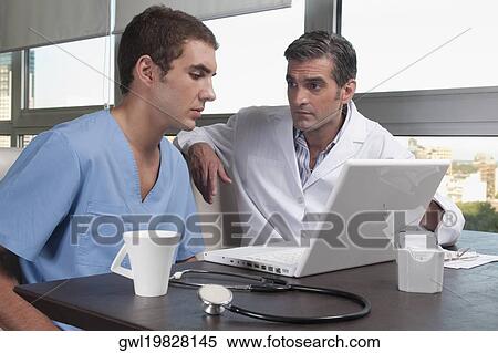 Doctors using a laptop in a cafeteria View Large Photo Image Stock Photography - Doctors using a laptop in a cafeteria. Fotosearch