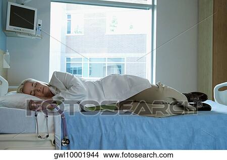 Exhausted female doctor sleeping on a patient's bed View Large Photo Image Picture - Exhausted female doctor sleeping on a patient's bed. Fotosearch