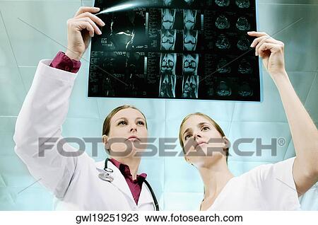 Female doctor and a nurse examining an X-Ray View Large Photo Image Stock Image - Female doctor and a nurse examining an X-Ray. Fotosearch