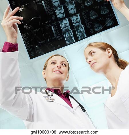 Female doctor and a nurse examining an X-Ray View Large Photo Image Stock Photo - Female doctor and a nurse examining an X-Ray. Fotosearch