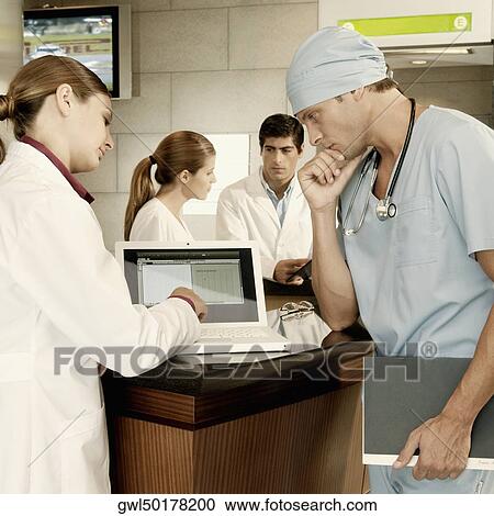 Female doctor and a surgeon discussing a medical report on a laptop View Large Photo Image Stock Image - Female doctor and a surgeon discussing a medical report on a laptop. Fotosearch
