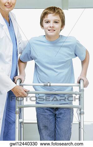 Female doctor assisting a boy with a walker View Large Photo Image Stock Image - Female doctor assisting a boy with a walker. Fotosearch
