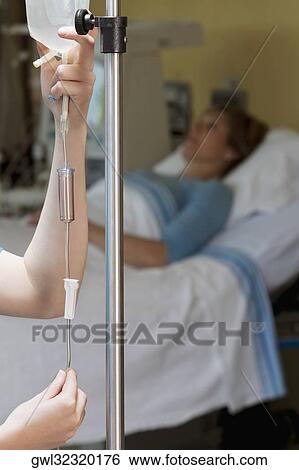 Stock Photograph - Female doctor checking a saline drip. Fotosearch