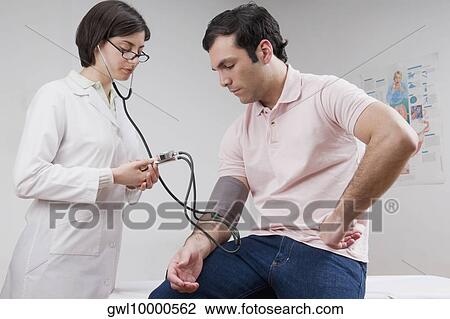 Stock Image - Female doctor checking man's blood pressure. Fotosearch