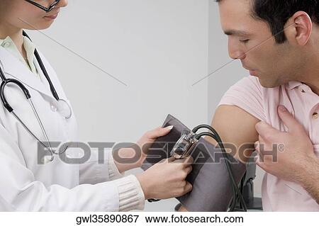 Female doctor checking man's blood pressure View Large Photo Image Stock Photo - Female doctor checking man's blood pressure. Fotosearch