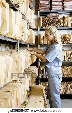 Female doctor checking records in a record room View Large Photo Image Stock Photo - Female doctor checking records in a record room. Fotosearch