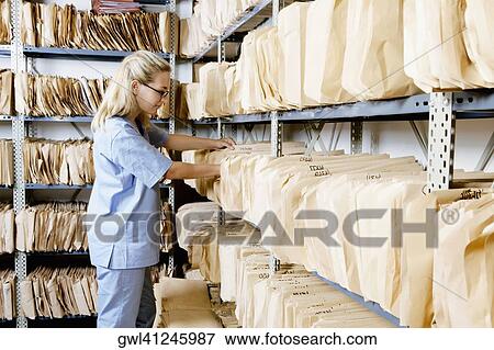 Female doctor checking records in a record room View Large Photo Image Stock Photo - Female doctor checking records in a record room. Fotosearch