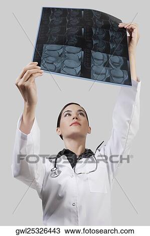 Stock Image - Female doctor examining an x-ray report. Fotosearch