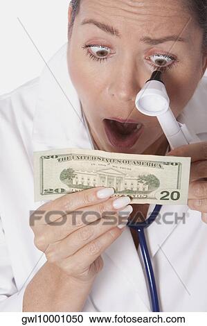 Female doctor examining currency notes with an otoscope View Large Photo Image Stock Image - Female doctor examining currency notes with an otoscope. Fotosearch