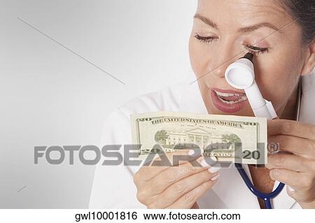 Female doctor examining currency notes with an otoscope View Large Photo Image Stock Photograph - Female doctor examining currency notes with an otoscope. Fotosearch