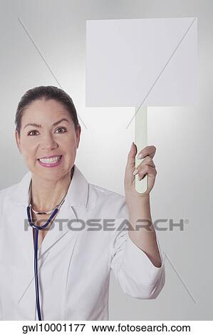 Female doctor holding a blank placard View Large Photo Image Stock Photo - Female doctor holding a blank placard. Fotosearch