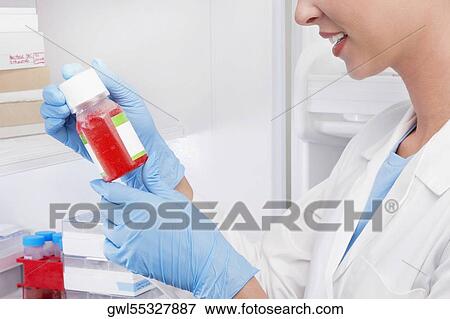 Female doctor holding a bottle of solution in a laboratory View Large Photo Image Stock Photo - Female doctor holding a bottle of solution in a laboratory. Fotosearch