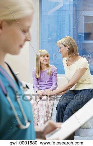 Female doctor holding a clipboard with patients in the background View Large Photo Image Stock Image - Female doctor holding a clipboard with patients in the background. Fotosearch