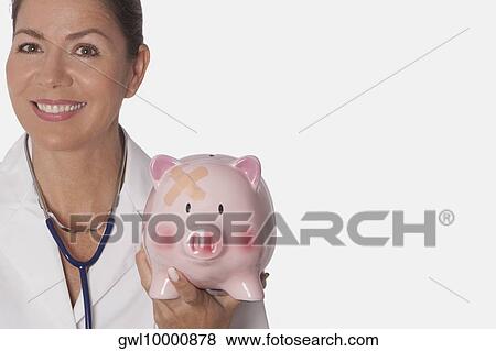 Stock Photo - Female doctor holding a piggy bank. Fotosearch