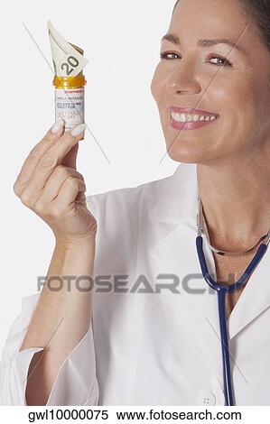 Female doctor holding a pill bottle with currency note View Large Photo Image Stock Photography - Female doctor holding a pill bottle with currency note. Fotosearch