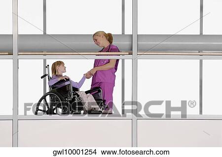 Female doctor holding hands of a patient in wheelchair View Large Photo Image Picture - Female doctor holding hands of a patient in wheelchair. Fotosearch
