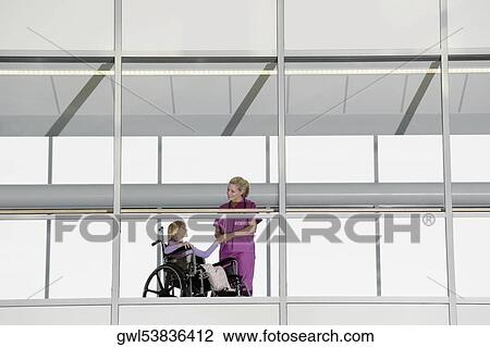 Female doctor holding hands of a patient in wheelchair View Large Photo Image Stock Image - Female doctor holding hands of a patient in wheelchair. Fotosearch