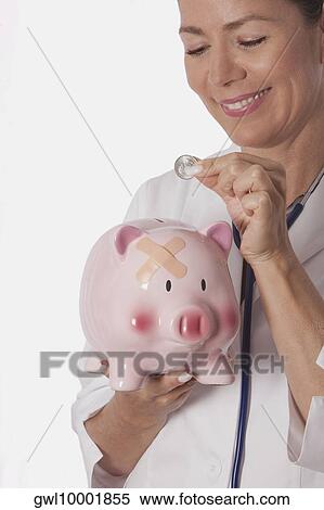 Female doctor inserting a coin into a piggy bank View Large Photo Image Stock Photography - Female doctor inserting a coin into a piggy bank. Fotosearch