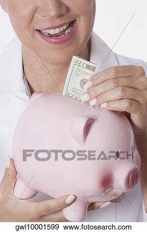 Female doctor inserting a currency note into a piggy bank View Large Photo Image Stock Photo - Female doctor inserting a currency note into a piggy bank. Fotosearch