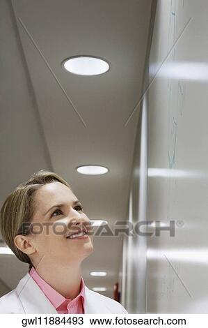 Stock Image - Female doctor looking at a whiteboard. Fotosearch