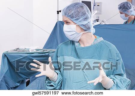 Stock Photo - Female doctor making a hand gesture in an operating room. Fotosearch
