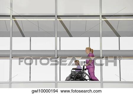 Female doctor pushing a patient in a wheelchair View Large Photo Image Picture - Female doctor pushing a patient in a wheelchair. Fotosearch
