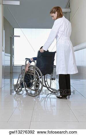 Female doctor pushing a patient in a wheelchair View Large Photo Image Stock Image - Female doctor pushing a patient in a wheelchair. Fotosearch
