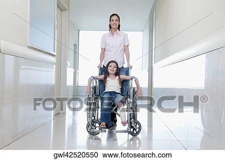 Female doctor pushing a patient in a wheelchair View Large Photo Image Stock Image - Female doctor pushing a patient in a wheelchair. Fotosearch